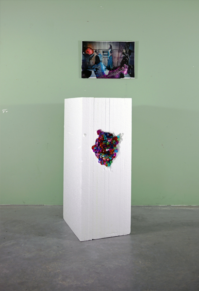 Installation of a sculpture in front of a small photograph